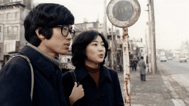 Couple talking at street bus stop in 70s