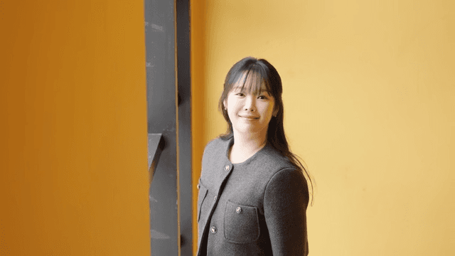 Profile of smiling woman looking out window in yellow room