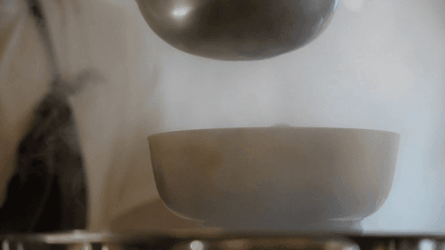 Ladle pouring soup into a steaming bowl