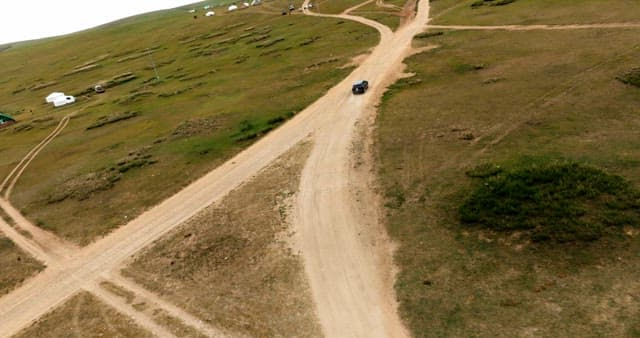 Car driving on a dirt road in open fields