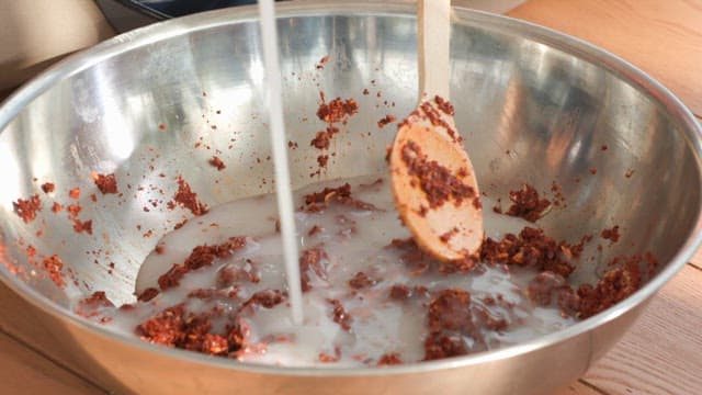 Mixing ingredients in a metal bowl using a wooden spoon