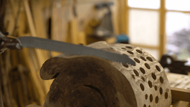 많은 구멍이 나있는 나무에 톱질을 시작하는 목공수