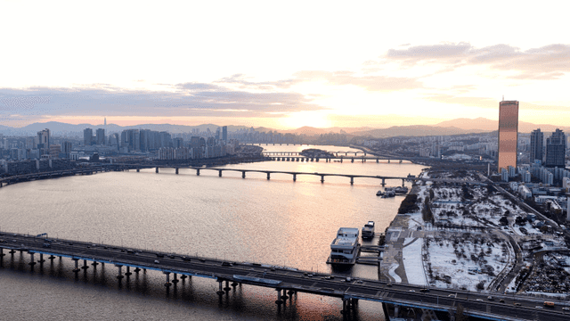 City landscape with river and bridge at sunset.