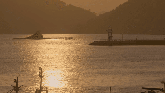 Lighthouse and fishing boats on the sea at sunset