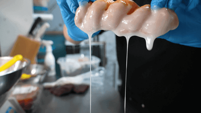 Gloved hands dipping pastry in glaze