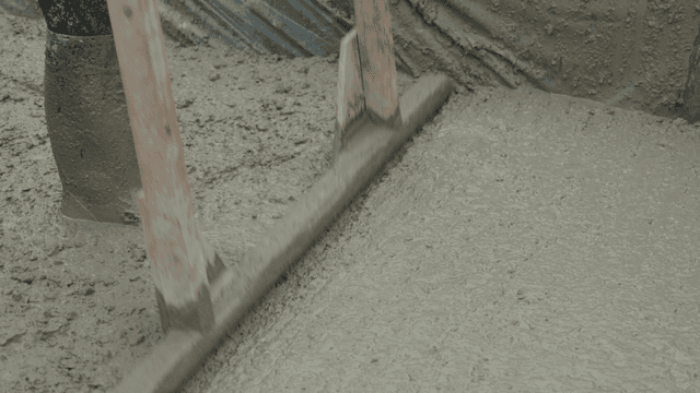 작업자가 도구로 젖은 콘크리트를 고르는 모습