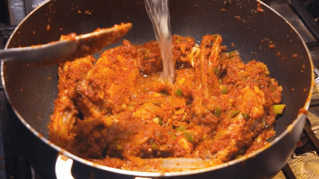 팬에서 조리 중인 매운 갈비에 물을 첨가하는 모습