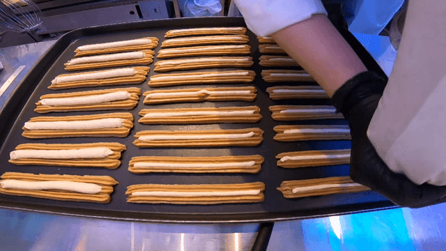 오븐 트레이에 츄러스 반죽을 짜는 사람