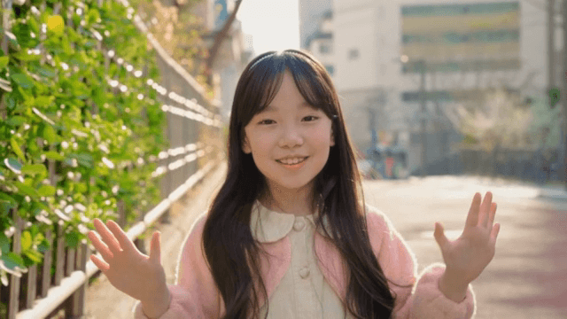 햇살 가득한 거리에서 손을 흔드며 미소 짓는 소녀