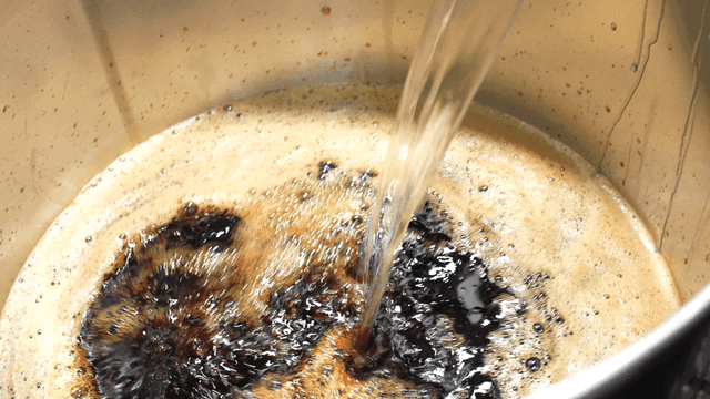 Scene of pouring seasoning liquid into large pot in kitchen