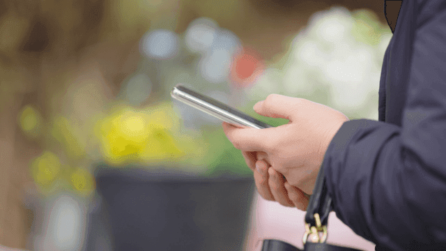Woman holding smartphone near flowers