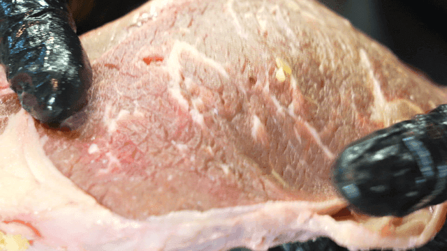 Raw meat being handled with gloves