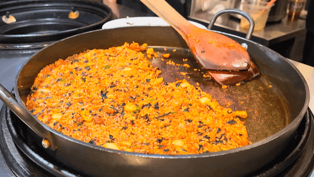 Wooden spatula and fried rice on iron plate