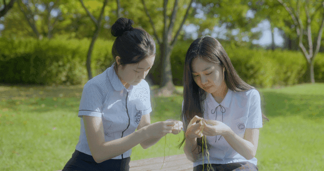 두 소녀가 우정 팔찌를 만드는 모습