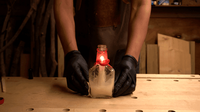 병에 불이 붙은 촛불을 들고 있는 사람