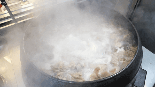 Steaming cauldron full of beef boiling in it