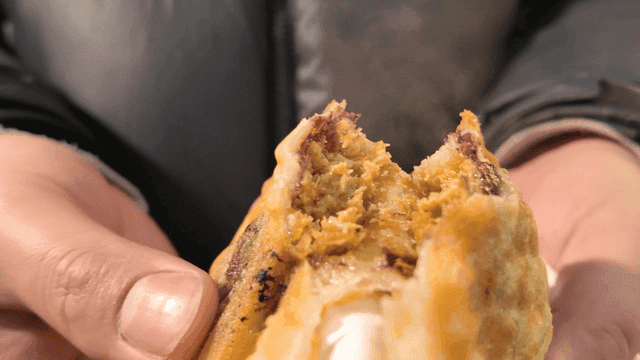 Person holding hot, chewy Dubai fish-shaped pastry.