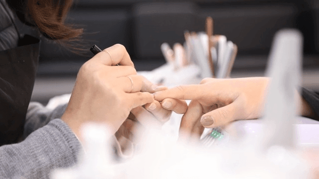 네일 아티스트가 손톱에 매니큐어를 바르는 모습