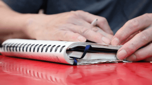 테이블 위에서 공책을 넘기는 사람