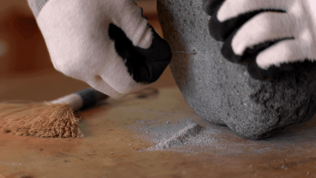 철사를 사용하여 돌 조각의 구멍을 정리하는 손