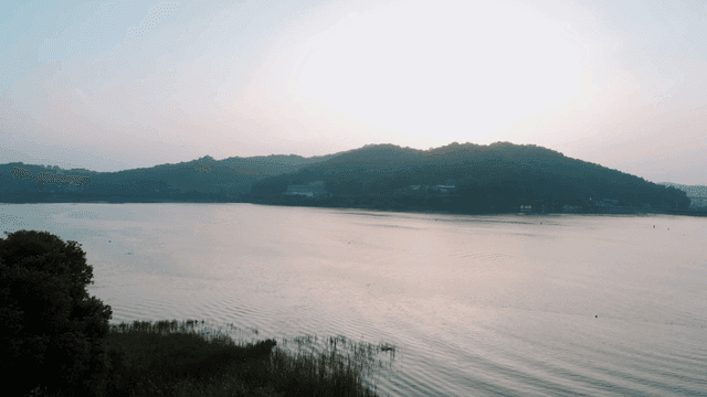 Sun rising over calm lake with distant hills visible
