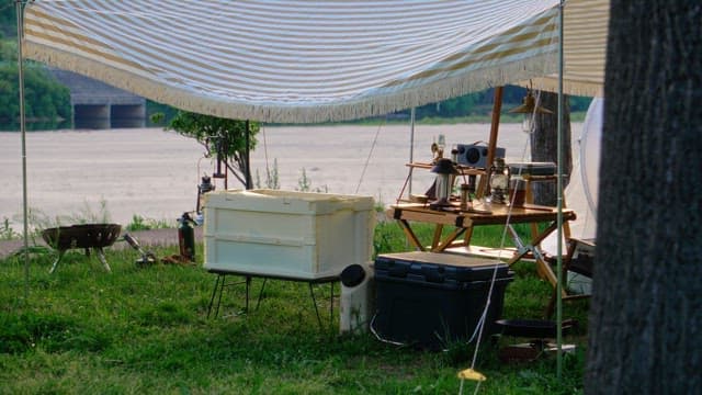 Camping equipment set up under a canopy on the grass