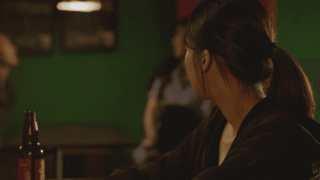 맥주병과 어두운 바에 앉아 있는 외로운 여성