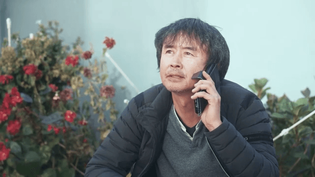 붉은 꽃 옆에서 전화하는 남자