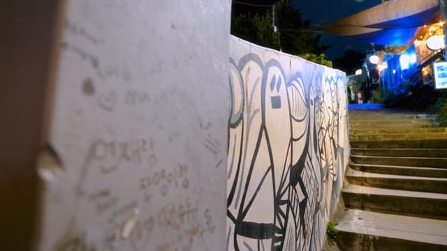 Graffiti on a wall along a dimly lit street