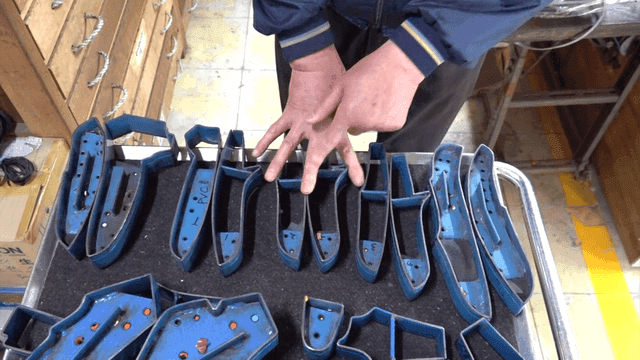 작업대 위 파란 금속 몰드를 점검하는 작업자