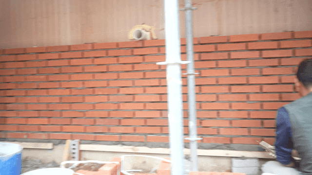 Workers building a brick wall at a site
