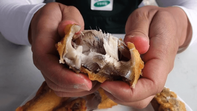 손으로 튀긴 생선을 쪼개는 모습