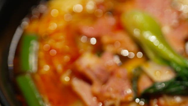 Steaming and spicy bowl of noodles with vegetables and meat