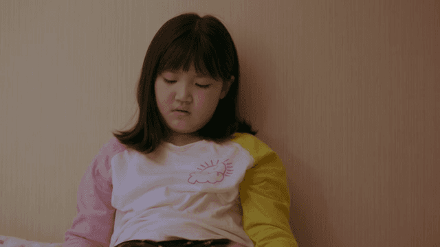 침대에 앉아 생각에 잠긴 아이