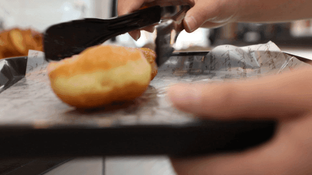 집게로 도넛을 쟁반에 놓는 장면