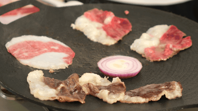 Beef and onions sizzling on grill