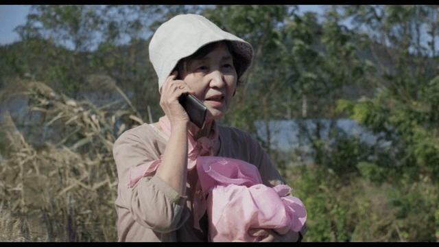 야외에서 보따리를 든 채 전화를 받는 노인