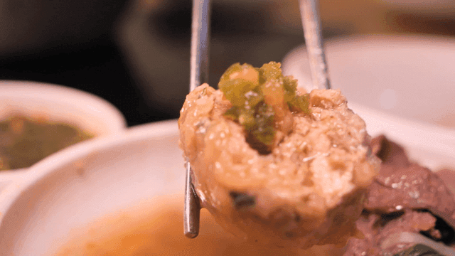 Rolled dumplings topped with green chili peppers in bowl