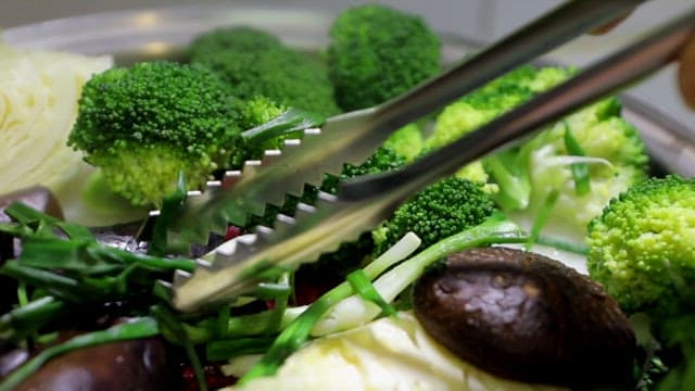 버섯, 브로콜리, 버섯 등 다양한 채소를 집게로 집는 모습