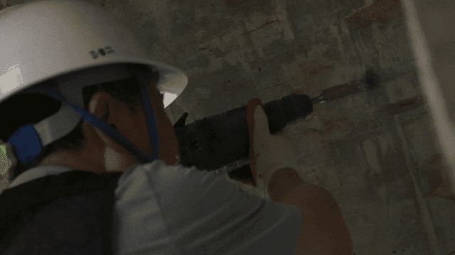 Worker drilling into a concrete wall