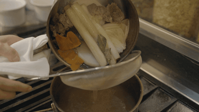 Straining broth with vegetables and meat