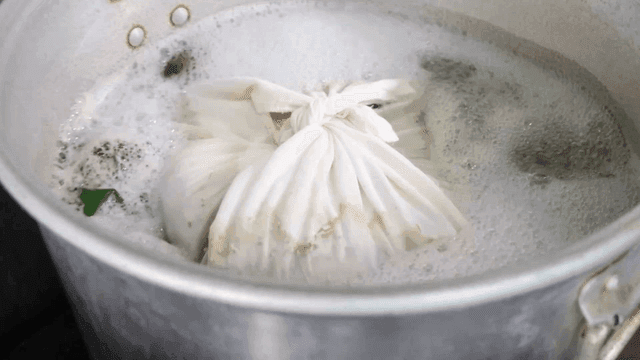 끓는 냄비에 주머니를 넣는 손