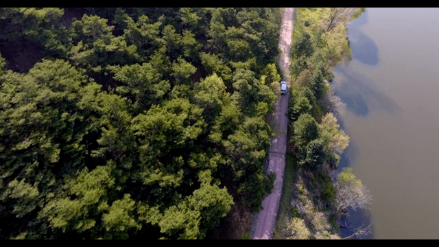 Car driving on the road between the river and the forest