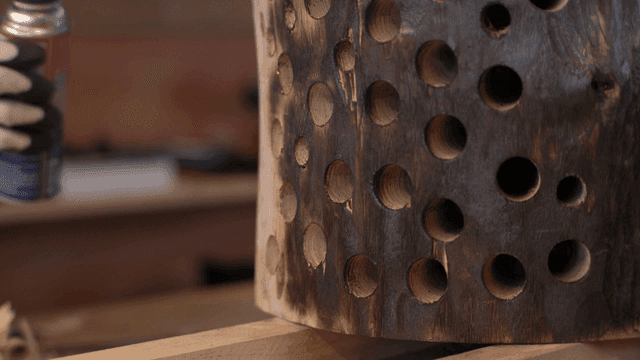 Burning the surface of perforated wooden barrel with torch
