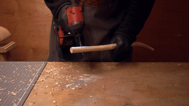 작업실에서 나무 막대를 드릴로 작업하는 사람