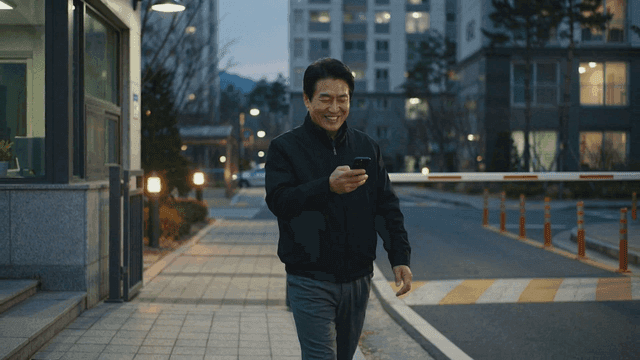 Man smiling while looking at his phone as he walks through apartment complex