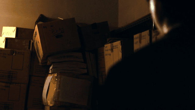 Person's back view looking at dark warehouse with boxes