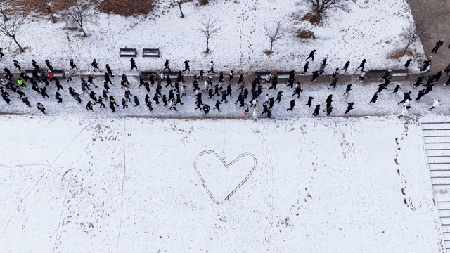 People running on snow-covered road and heart shape in snow