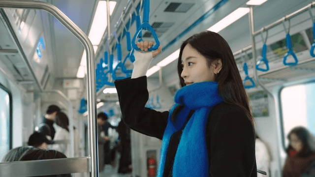 Profile of a woman standing on the subway, holding onto a handrail