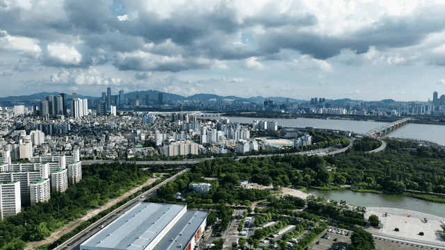 Vast city landscape beneath river and wide, cloudy sky